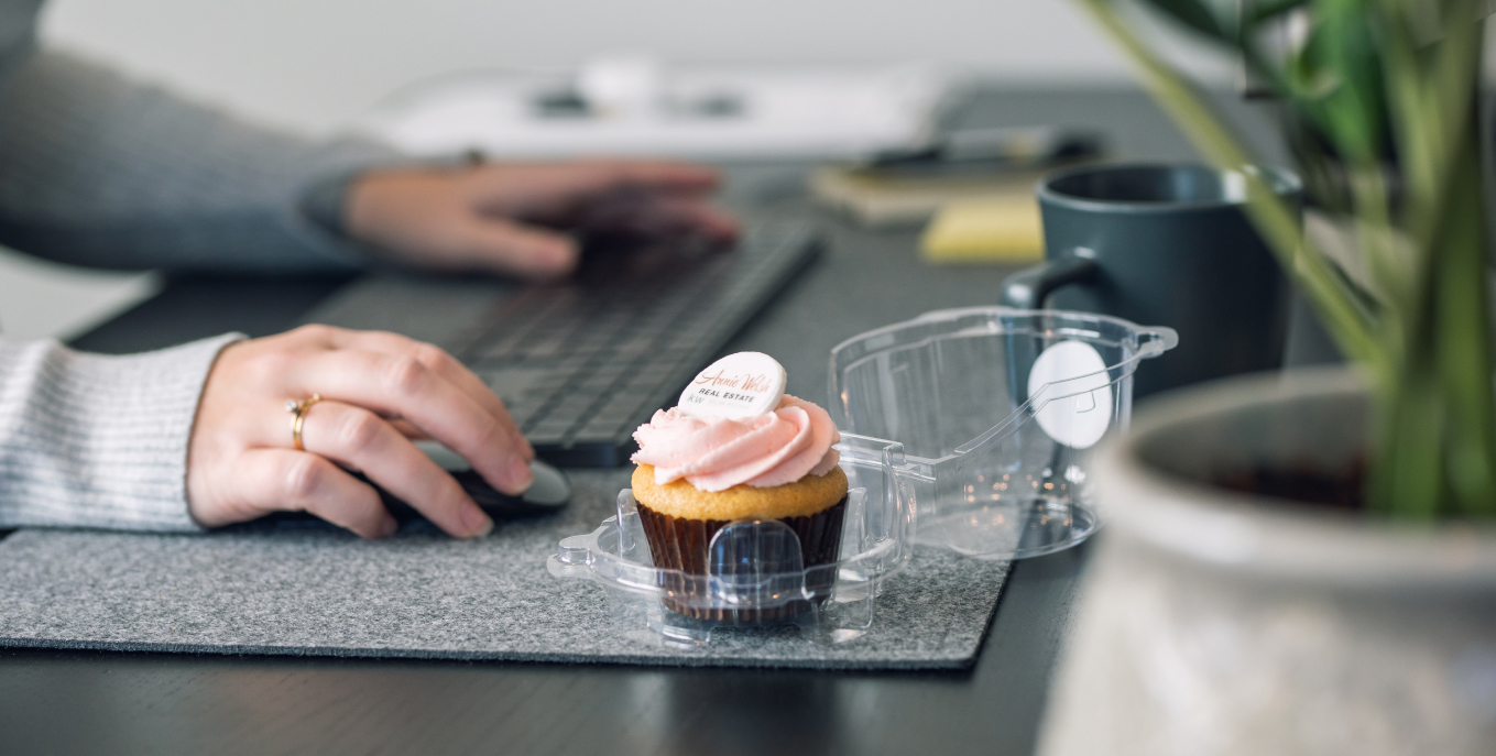 Cupcake on desk with person working with mouse and keyboard